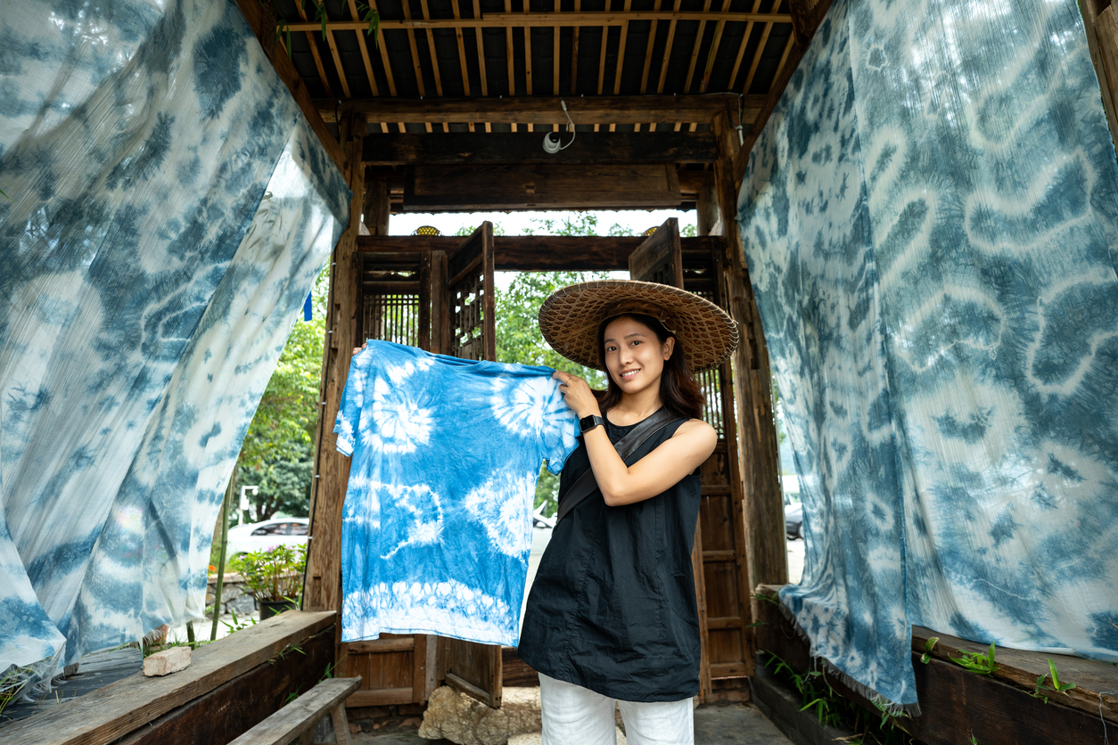 Smiling tourist showing off self-made tie-dye artwork in Yunnan