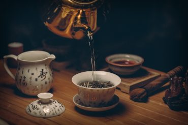 Pouring freshly brewed Pu-erh tea into a small tasting cup